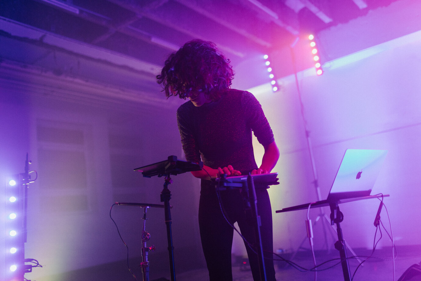 Komponistin in Residence Svetlana Maraš in Aktion: sie steht in einem mit lila Scheinwerfern beleuchteten Raum, mit den Händen an elektronischen Instrumenten.