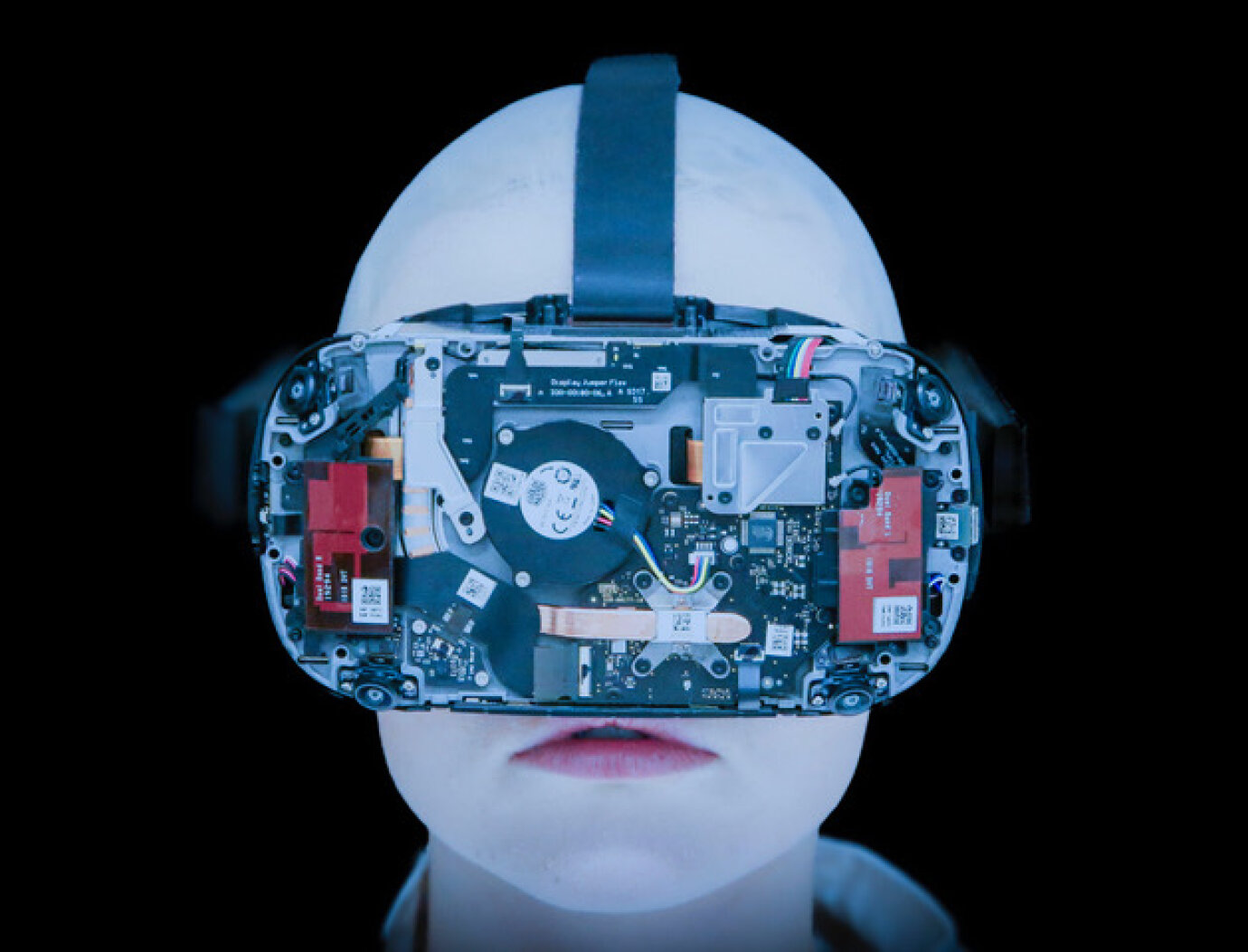 Ein kahl geschorener, weisser Kopf vor schwarzem Hintergrund. Er trägt eine Art grosse Brille, die das Gesicht fast verdeckt und an Virtual Reality Brillen erinnert. 