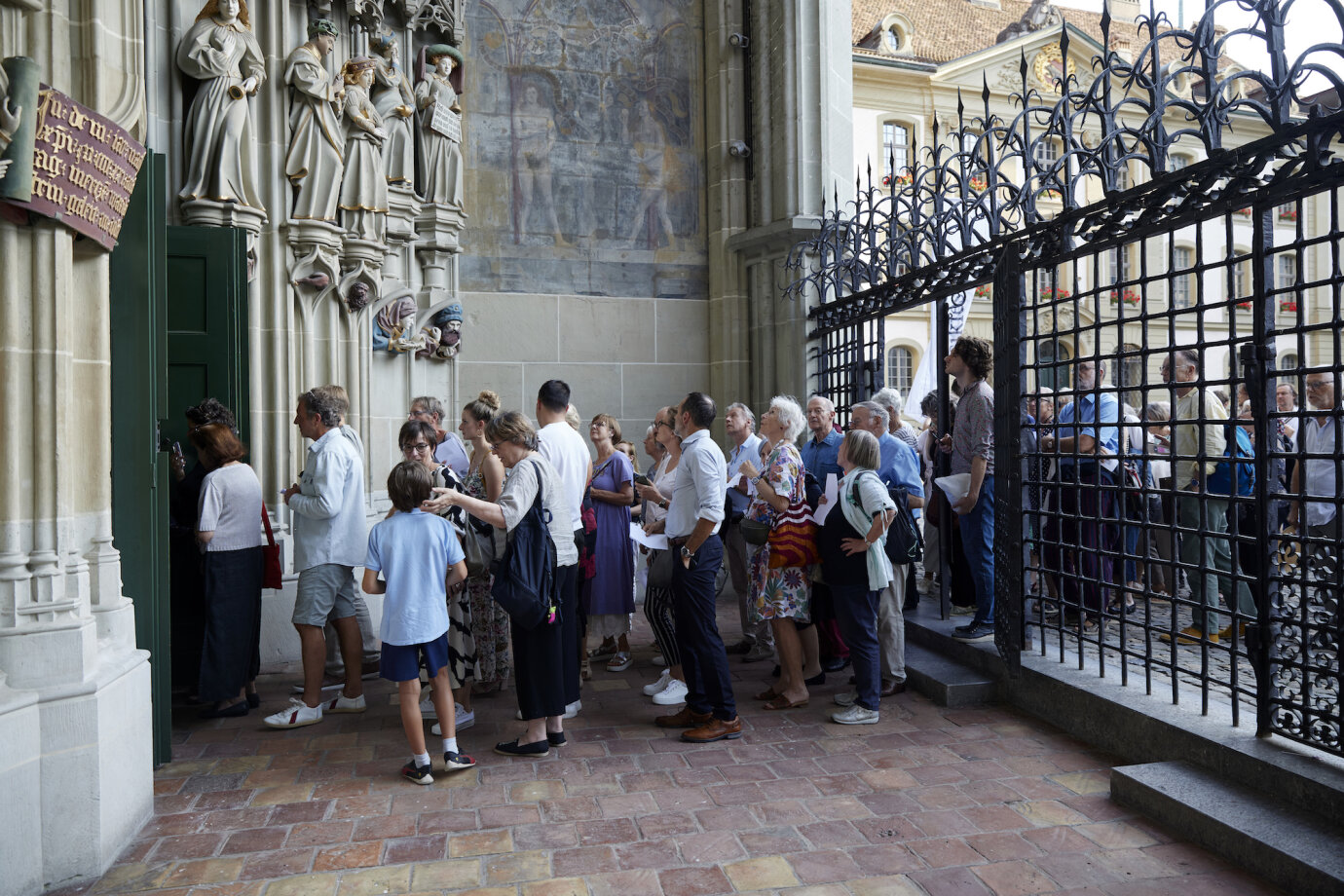 Eine lange Schlange Menschen wartet vor dem Eingang des Berner Münster auf Zutritt. 